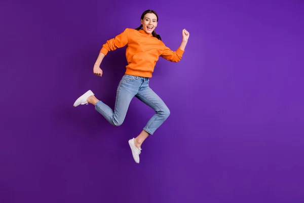 Foto de cuerpo completo de la joven alegre positiva saltar correr después de descuentos sentir contenido usar ropa deportiva vaqueros zapatillas blancas aisladas sobre violeta color púrpura fondo —  Fotos de Stock