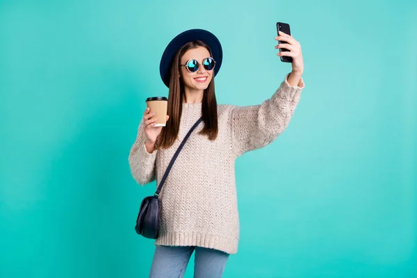 Портрет стильної модної позитивної леді робить самопортрет на її мобільному телефоні носіння шапки капелюха білий в'язаний джемпер ізольований на слізному бірюзовому кольоровому фоні — стокове фото