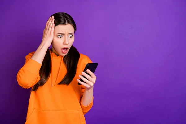 Portrait of astonished youth girl use her cellphone read feednews comment on social network accounts shout wow omg wear sporty wear isolated over violet purple color background