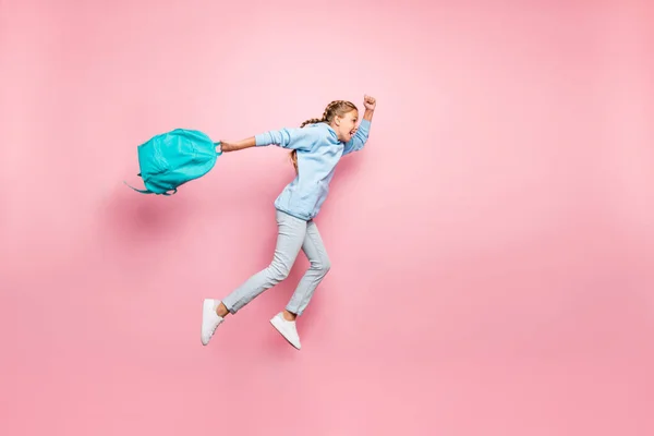 Full length body size side profile foto van vrolijke gekke extatische dolblij schoolkind gooien zijn rugzak weg met ejans denim blauwe trui sweater schoeisel springen geïsoleerde pastel kleur — Stockfoto