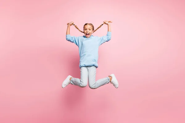 Foto de perfil de cuerpo completo de la señora bonita saltando alto sosteniendo trenzas largas frescas en las manos disfrutar de ropa de fin de semana soleado traje casual aislado pastel color rosa fondo —  Fotos de Stock