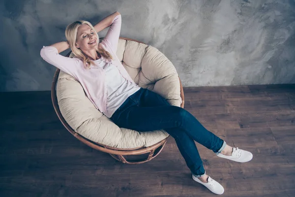 Top above high angle view photo of peaceful chappy content middle aged woman lying in armchair feel candid dream about future vacation wear pastel color denim jeans in living room indoor — Φωτογραφία Αρχείου