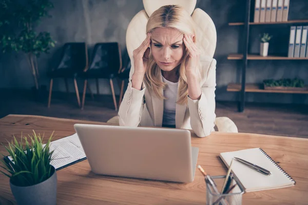 Foto de mulher cansada exausta trabalhando como jornalista para a corporação olhando para o laptop sentado na área de trabalho sofrendo de dor de cabeça dor de cabeça — Fotografia de Stock