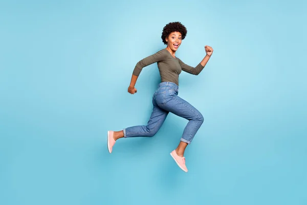 Full length body size φωτογραφία του χαρούμενα γρήγορη μαύρη γυναίκα άλμα προς εμπορικό κέντρο όσο το δυνατόν γρηγορότερα φορώντας τζιν τζιν που απομονώνονται σε έντονο μπλε χρώμα φόντο — Φωτογραφία Αρχείου
