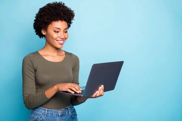 Foto de alegre criativo bonito bom trabalhador freelance vestindo jeans jeans segurando dispositivo eletrônico com as mãos laptop trabalhando com tecnologia isolada sobre cor viva fundo azul — Fotografia de Stock