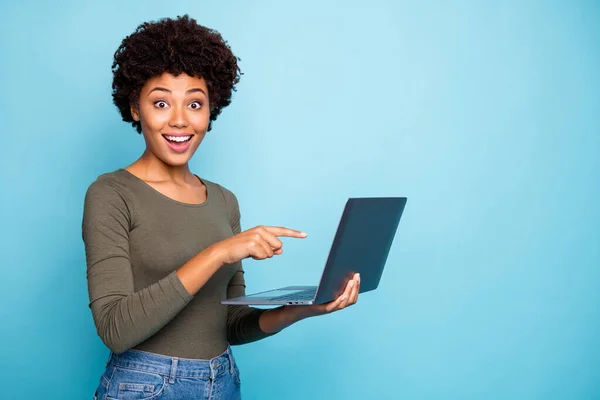 Photo de mignon élégant modèle noir tendance pointant vers ordinateur portable vous recommandant de l'acheter demandant à suivre sur les médias sociaux portant un jean pull en hreen denim isolé couleur vive fond bleu — Photo