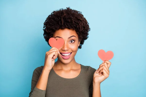 Close up photo of amazed excited emotions expression afro american girl hold little paper card close cover her face have fun on date for 14-february wear green sweater isolated over blue color — Stock fotografie