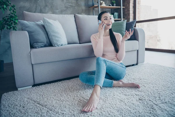 Foto van een mooie dame die telefoonhanden vasthoudt en met vrienden praat leunende sofa zit vloer op comfortabele pluizige tapijt dragen pullover en jeans in appartement — Stockfoto