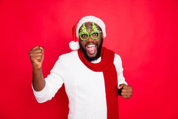 Foto de engraçado homem de pele escura no humor fresco encontrar convidados no novo ano festa desgaste x-mas evergreen árvore especificações branco santa cap cachecol e suéter isolado fundo vermelho — Fotografia de Stock