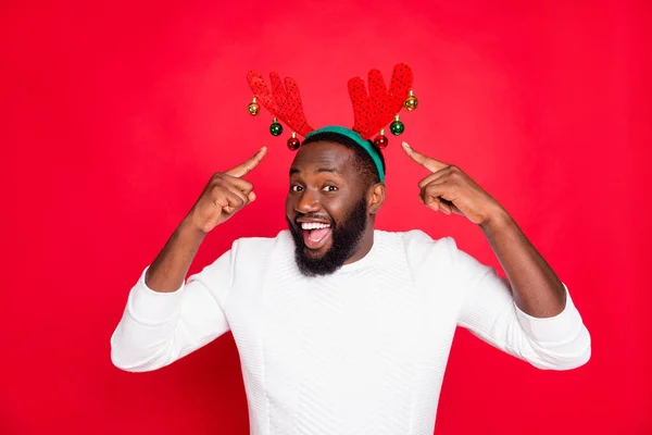 Retrato de asombrado pelo castaño sorprendido loco hombre de piel negra punto en cuernos de venado rudolf disfrutar de su accesorio para la fiesta de Nochebuena fiesta desgaste jersey blanco aislado color rojo fondo — Foto de Stock