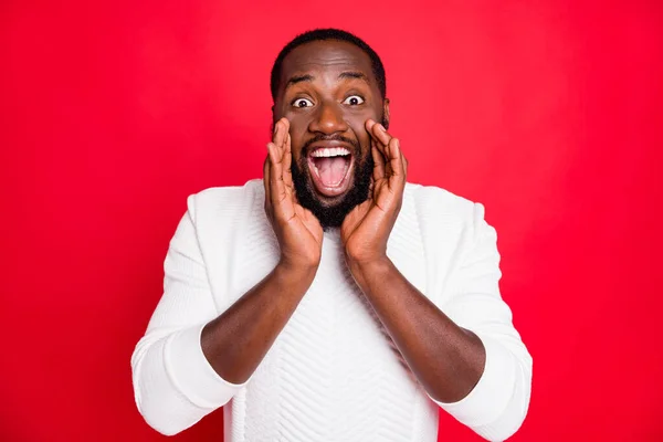 Luister naar nieuwe promo. Portret van gekke funky Afrikaanse man hand in de buurt mond schreeuwen advertenties delen vertrouwelijke informatie slijtage stijl witte trui geïsoleerd over rode kleur achtergrond — Stockfoto
