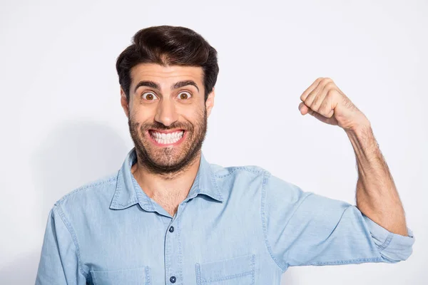 Foto di incredibile bel ragazzo alzando il braccio mostrando perfetta forma bicipiti esprimendo forza indossare casual camicia di jeans isolato sfondo di colore bianco — Foto Stock