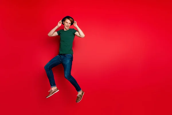 Foto in voller Größe von lustigen flippigen Kerl in blauem Samt Kopfbedeckung springen haben Freizeit im Frühling Urlaub tragen Jeans Kleidung Turnschuhe isoliert über rotem Hintergrund — Stockfoto