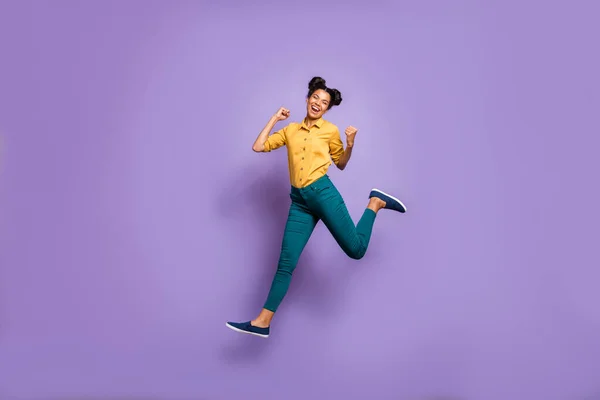 Foto de perfil de cuerpo completo de la señora de piel bastante oscura saltando alto celebrando la victoria del equipo de fútbol favorito desgaste casual pantalones de camisa amarilla aislado color púrpura fondo —  Fotos de Stock