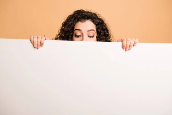 Foto de la señora divertida que no muestra la cara llena sosteniendo dedos letrero blanco grande que presenta información novedosa mirando se preguntó fondo de color pastel beige aislado — Foto de Stock