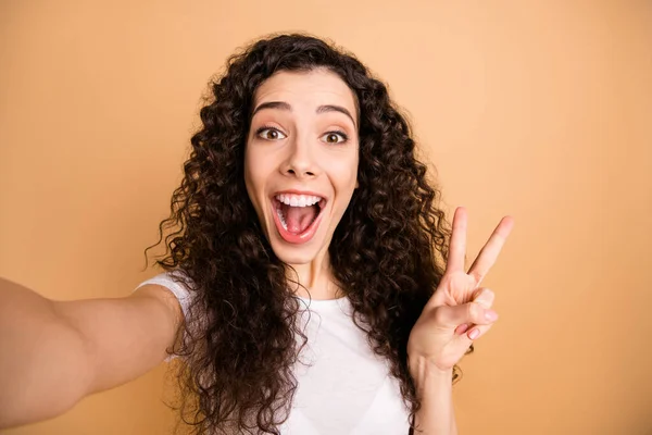 Närbild foto av fantastiska dam att göra selfies toothy leende visar v-tecken symbol glad bära vit casual kläder isolerad beige pastell färg bakgrund — Stockfoto