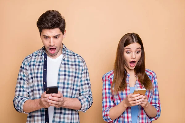 Omg. Retrato de cônjuges impressionados blogueiros usam navegação smartphone obter notificação de rede social se sentir estupor olhar na tela desgaste xadrez roupa casual isolado sobre fundo cor pastel — Fotografia de Stock