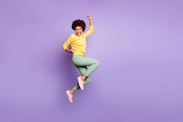 Full body photo of delighted afro american girl celebrate autumn spring jackpot victory raise fists scream yeah wear yellow sweater green pants trousers isolated over violet purple color background — 图库照片