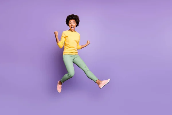 Full size photo of crazy brunette hair mulatto girl hear incredible fall spring lottery victory feel impressed jump raise fists scream yeah wear casual style outfit isolated violet color background — Stock Fotó