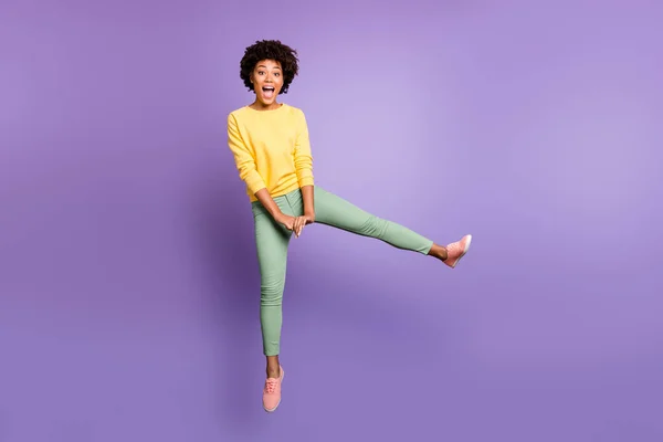 Πλήρης φωτογραφία μεγέθους χαρούμενα αστεία funky έφηβος afro american κορίτσι άλμα διασκεδάσουν το φθινόπωρο Σαββατοκύριακα άνοιξη ελεύθερο χρόνο φορούν κίτρινο πουλόβερ πράσινο παντελόνι παντελόνι απομονώνονται σε μωβ βιολετί χρώμα φόντο — Φωτογραφία Αρχείου