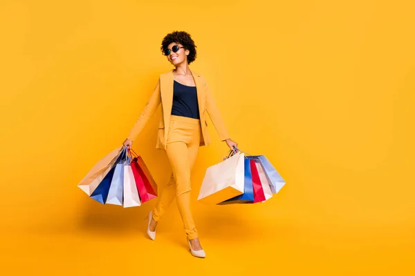 Full size foto van positieve vrolijke meisje hebben vrije tijd voelen droom dromerige hold tassen gaan van winkelcentrum dragen stijl blazer broek stiletto 's geïsoleerd over gele kleur achtergrond — Stockfoto