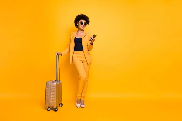 Full size photo of focused brown wavy hair tourist girl use smartphone hold bag try book taxi reach destination on autumn weekends wear jacket pants high-heels isolated yellow color background — Stock Photo, Image