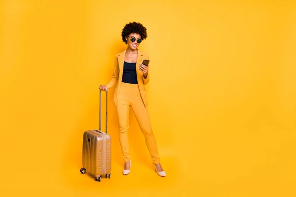 원문 기사보기 관광 컨셉 완전 한 바디 사진 긍정적 인 갈색 곱슬머리 여자가 스마트폰을 사용하는 방법 GPS 검색 주말에는 하이힐 바지를 입고 노란 색 배경을 분리 된 가방을 소지 — 스톡 사진