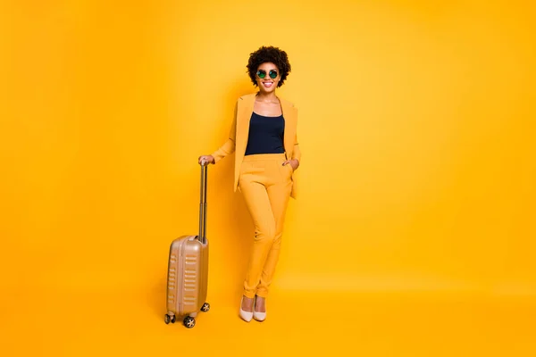 Full length photo of charming chic stunning dark skin girl feel positive ready go abroad for trip wear fashionable outfit trousers shoes isolated over yellow color background — 스톡 사진