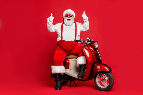 Portret jego ładny brodaty wesoły wesoły funky pewność siebie Santa Claus hipster siedzi na motocyklu pokazując kciuk odizolowany na jasny żywy połysk żywy czerwony kolor tło — Zdjęcie stockowe