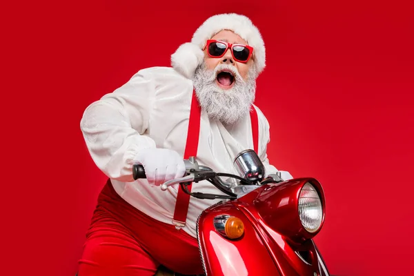 Portret jego ładny brodaty siwowłosy wesoły zadowolony funky Santa hipster jazda na motocyklu spędzanie chłodny grudzień noc noel wakacje izolowane na jaskrawy blask żywy czerwony kolor tło — Zdjęcie stockowe