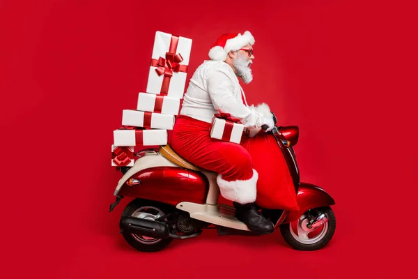 Güzel sakallı, odaklanmış, komik, şişman Noel Baba 'nın profili. Moped yığını üzerinde yolculuk eden, kış perisi alışverişleri. Parlak, parlak, parlak, kırmızı bir arka planda izole edilmiş. — Stok fotoğraf