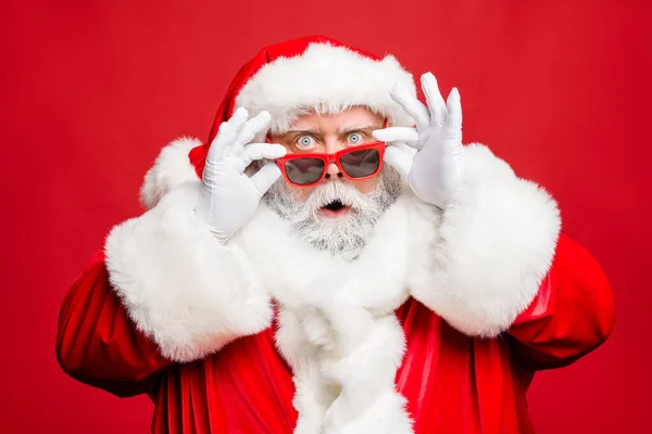 信じられないクリスマスの父の衣装で印象的な退職者の肖像画は悪い光景を見ることができません冬のショッピング割引販売は、赤の背景に隔離されたトレンディーなキャップ帽子手袋を着用 — ストック写真