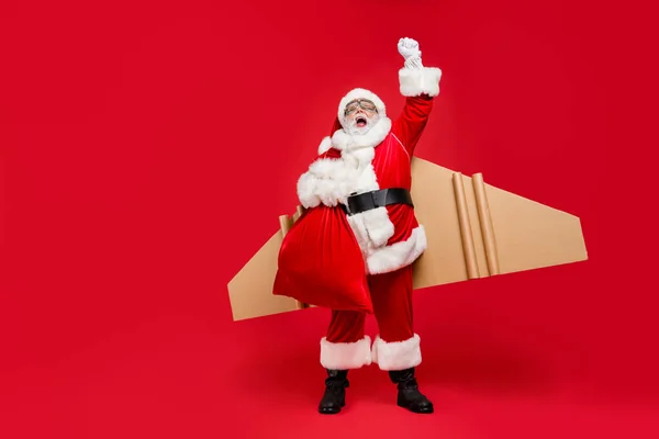 Ay 'a gidip gelmek. Çılgın komik süper Noel Baba 'nın tüm vücut fotoğrafları turbo uçağına hediye vermek için acele edin. Kanatlar yukarı. Kırmızı arka planda izole edilmiş şapka gözlüğü takın. — Stok fotoğraf