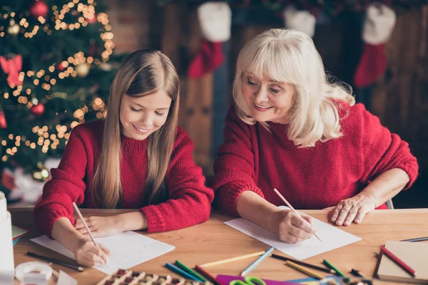 Porträtt av trevlig attraktiv härlig inspirerad glad mormor pre-teen barnbarn skriver festlig önskan brev till Santa Christmastime på dekorerad industriell tegel trä loft stil ljus interiör hus — Stockfoto