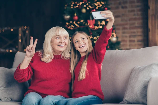 Närbild porträtt av trevlig attraktiv glad glad glad mormor liten pre-teen långhårig skolflicka tar gör selfie visar v-tecken på dekorerad industriell loft stil interiör hus — Stockfoto