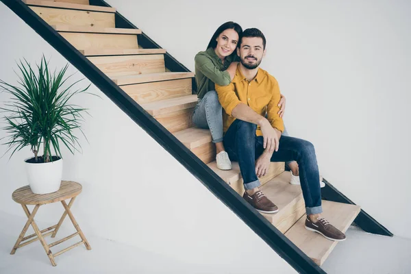 현란 한 실내 방에서 새로운 아파트로 이사하는 미남 과 그 의아름다운 부인 이 계단 위에 앉아 있는 사진 전체가 평범 한 옷을 입고 있다 — 스톡 사진