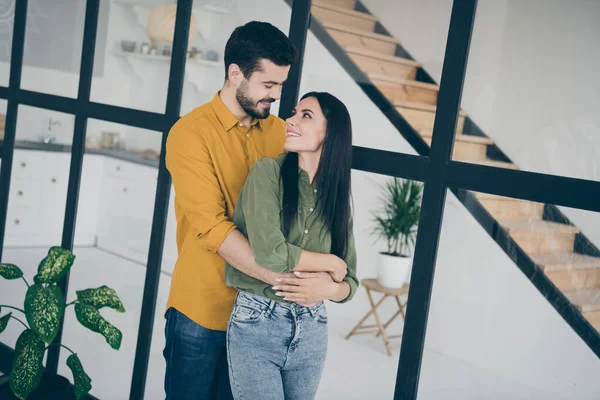 Foto de chico guapo y su hermosa esposa mujer mirando ojos tiernos se trasladó a un nuevo abrazo plano a cuestas en el interior moderno de moda plana en interiores usar ropa casual — Foto de Stock