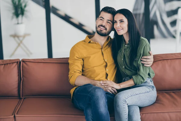 Foto do cara e sua esposa senhora se mudando para a nova casa de campo como pessoas casadas abraçando as mãos sentado sofá no apartamento moderno dentro de casa usam roupas casuais — Fotografia de Stock