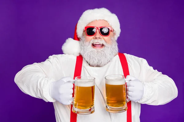 Close-up portret miło zadowolony wesoły wesoły wesoły pozytywny brodaty Mikołaj gospodarstwa w rękach dwa kubki picia piwa o zabawy odizolowane na jasny żywy połysk żywy fioletowy liliowy tło — Zdjęcie stockowe
