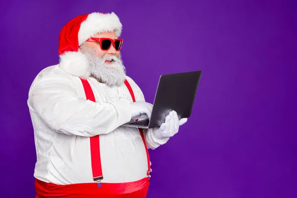 Profile side view portret jego miły pewny siebie wesoły wesoły brodaty Santa gospodarstwa w rękach laptop wpisując przeglądanie wi-fi odizolowany na jasny żywy połysk żywy fioletowy liliowy tło — Zdjęcie stockowe