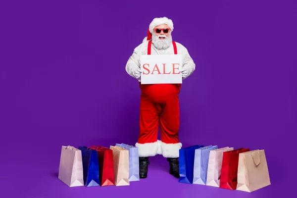 Plná délka tělesné velikosti pohled na jeho on pěkný jistý veselý pozitivní vousatý tlustý tuk Santa demonstrující prodej plakát sezóna oblečení izolované na světlé živé lesk pulzující fialové šeříkové pozadí — Stock fotografie