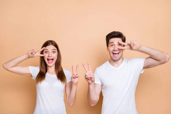 Porträtt av hans he he her she nice attraktiv härlig funky överlycklig glad glad glad glad glad par team bär vit t-shirt visar v-tecken isolerad över beige pastell färg bakgrund — Stockfoto