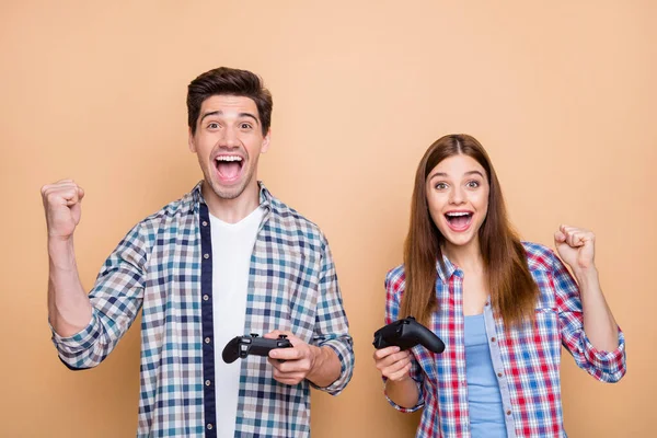 Foto av glada positiva casual vit brun hår par spelar playstation videospel jublar med segern håller joysticks med händerna isolerade över beige pastell färg bakgrund — Stockfoto