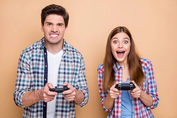 Fotografie legrační funky pár dvou lidí, kteří hrají videohry s přítelkyní poráží svého přítele šklebí v hněvu izolované přes béžové pastelové barvy pozadí — Stock fotografie