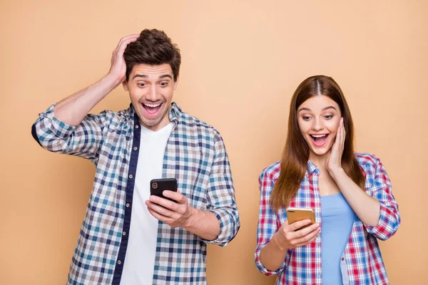 Retrato de su ella ella agradable atractivo encantador sorprendido maravillado alegre pareja con camisa a cuadros usando celular viendo smm media suscripción aislado sobre beige pastel color fondo —  Fotos de Stock