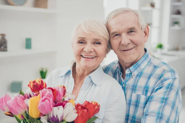 Primer plano retrato de ella ella su él dos agradable atractivo alegre alegre alegre alegre adorable gente abuelita sosteniendo en las manos grande fresco flor natural felicitaciones primavera en blanco claro interior sala de estar —  Fotos de Stock