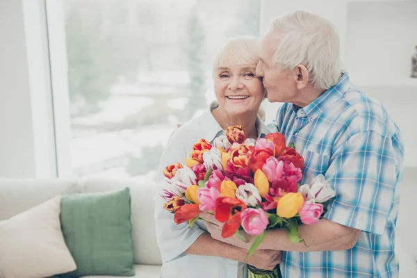 Retrato de ella ella su él dos agradable alegre alegre alegre dulce tierna gente abuela recibir grandes tulipanes florales frescos felicitaciones primavera primavera en blanco claro interior sala de estar —  Fotos de Stock