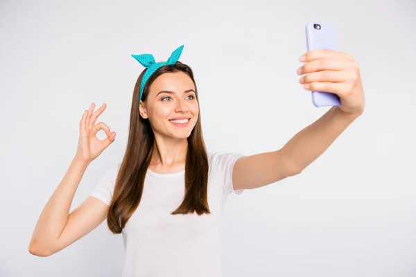 Retrato de chica positiva alegre en los fines de semana de verano tomar selfie en el teléfono inteligente mostrar signo ok recomendar anuncios promo usar ropa de estilo retro aislado sobre fondo de color blanco — Foto de Stock