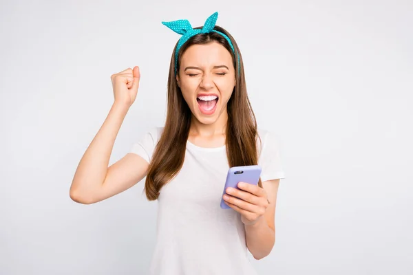 Портрет позитивної веселої дівчини, яка використовує свій мобільний телефон, отримує сповіщення про перемогу в онлайн-лотереї піднімають кулаки кричать так, що одяг ретро-стилю ізольований на білому тлі — стокове фото