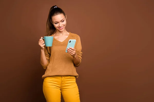 Foto de hermosa atractiva linda y encantadora novia fascinante charlando por teléfono sosteniendo la taza de té con la lectura de la mano noticias aisladas sobre el fondo de color pastel marrón — Foto de Stock